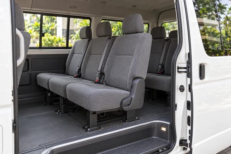 Grey fabric passenger-van seats and boarding step viewed through an open sliding door
